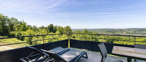Una terraza con mesa y sillas, con vistas a un paisaje verde exuberante.