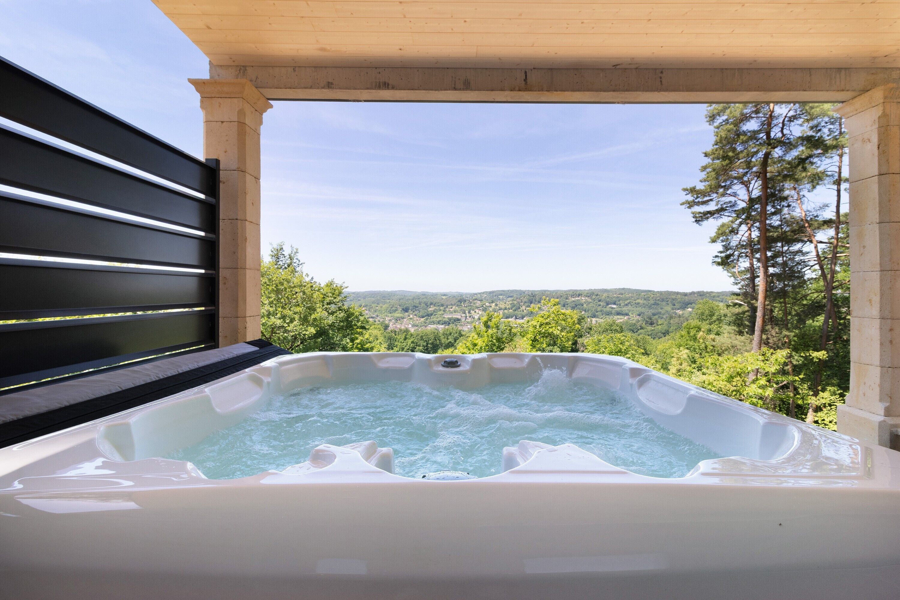 A hot tub with a view of a forest and hills.