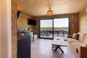 Interior em madeira com cozinha, sala de jantar e porta de vidro deslizante para um pátio exterior.