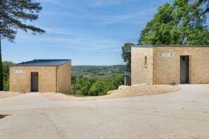 Dois edifícios de pedra com placas, uma identificada como 'Eden' e outra como 'Cedar', emoldurados por árvores e uma paisagem distante.