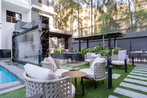 Eine moderne Außenpatio mit Pool, Korbmöbeln und einer Pergola.