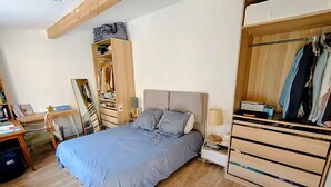 Un dormitorio con cama, mesita de noche, lámpara, armario y un escritorio con silla.