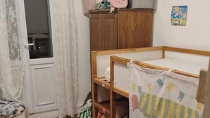Un cuarto de juegos infantil con una cama, unidad de almacenamiento y una alfombra colorida.