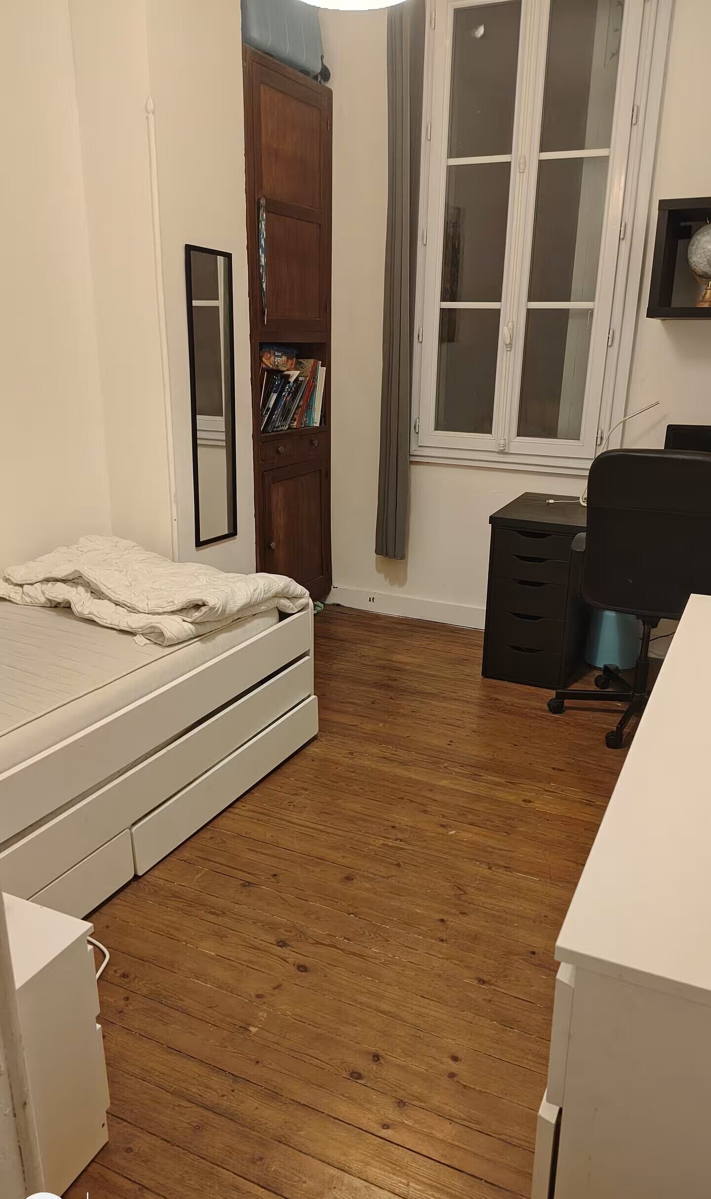 A bedroom with a bed, a wardrobe, a desk, and a window.