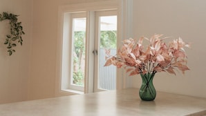 Et køkken med en marmorbordplade, en grøn vase med rosa blade, og en dør til et udendørs område.