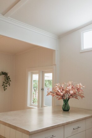 Eine Küche mit einer Marmorarbeitsplatte, einer grünen Vase mit rosa Blättern und einer Tür zu einem Außenbereich.