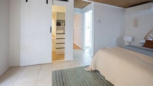 Et soveværelse med seng, skab, skydedør, et natbord og en lampe.