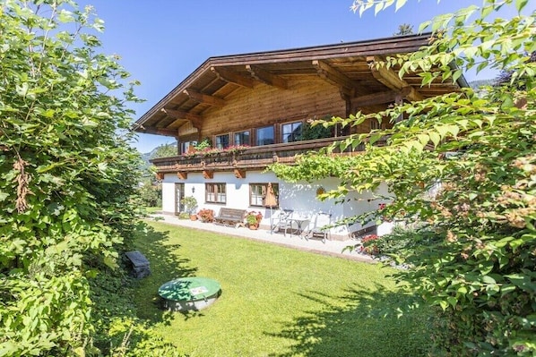 A traditional wooden chalet with a balcony, surrounded by lush greenery. - Holiday apartment in Waidring with Wi-Fi (Waidring)