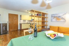A dining area with a table set for two, a bottle of wine, and a fruit bowl. - Holiday apartment in Waidring with Wi-Fi (Waidring)