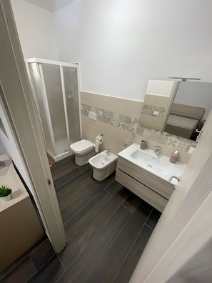 Un bany modern amb dutxa, vàter, bidet i rentapel.