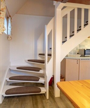 Eine Treppe mit Holzvertäfelung und ein Küchenbereich mit weißen Schränken und einer Arbeitsplatte.