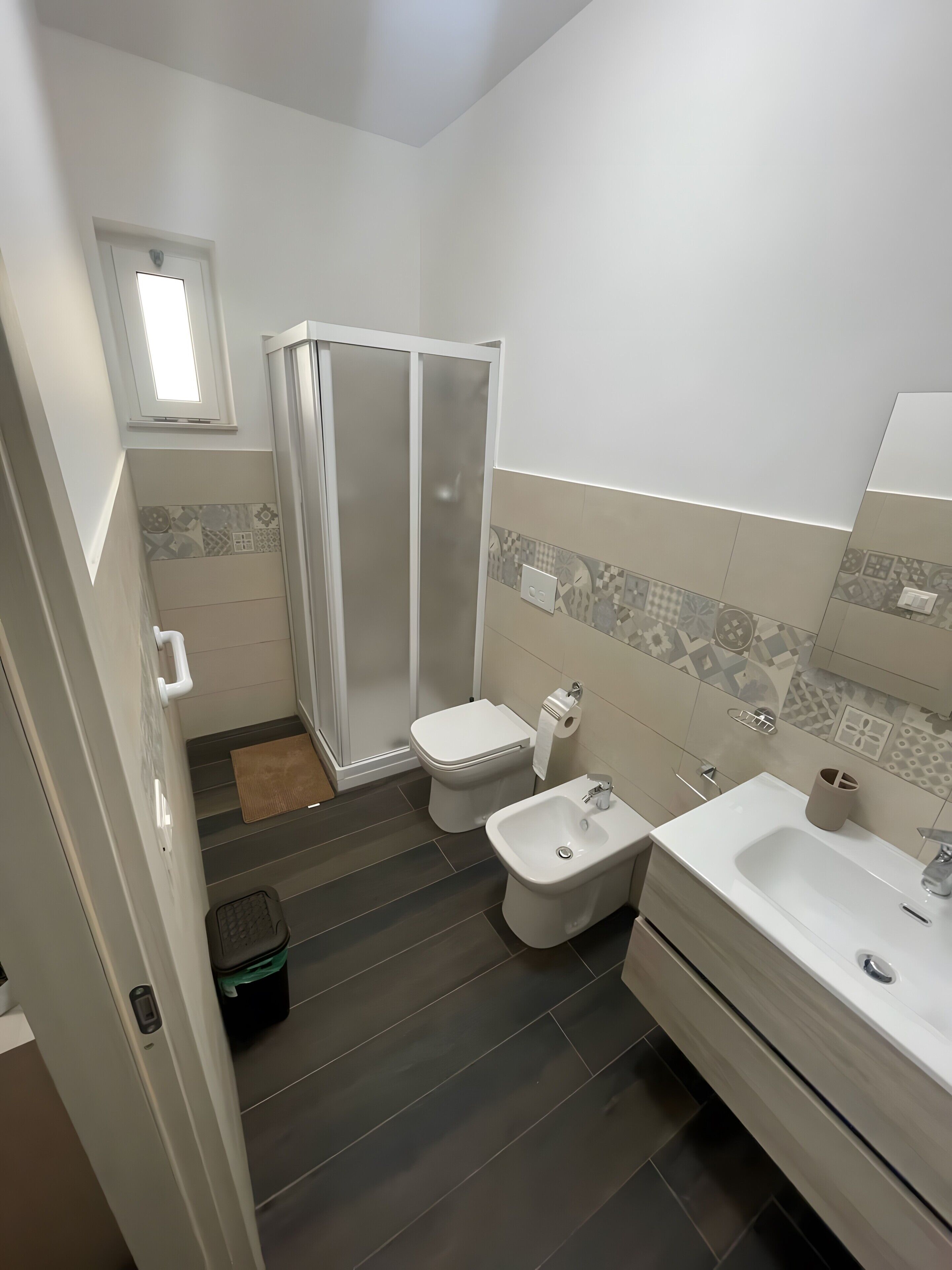 Une salle de bain équipée d’une douche, de toilettes, d’un bidet, d’un lavabo et dont les murs sont recouverts de carrelage.