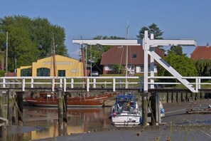 Eine Brücke über einen Kanal mit Booten, einem gelben Gebäude und einer weißen Struktur.