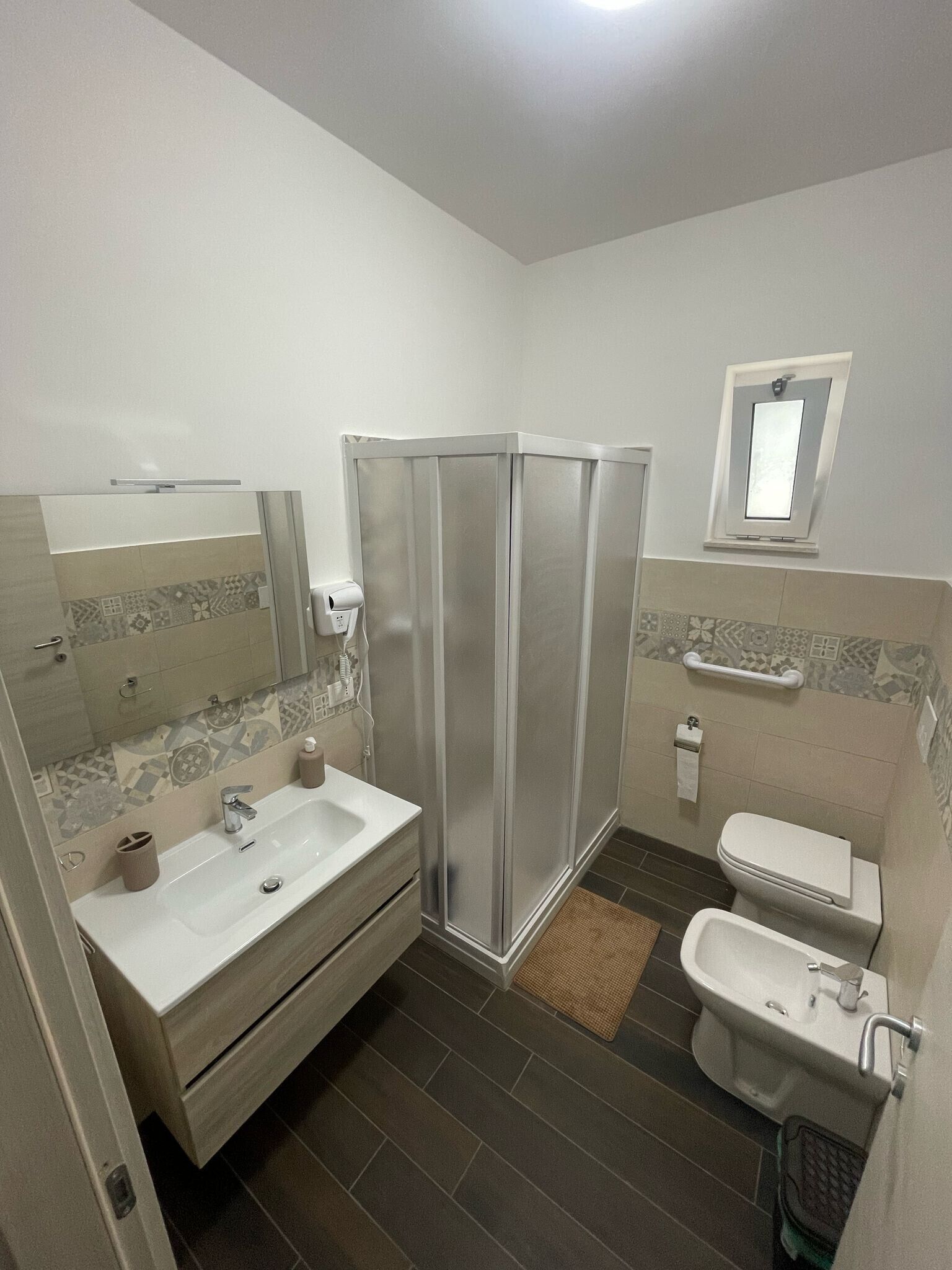 Ein Badezimmer mit Dusche, Waschbecken, Toilette und Spiegel.