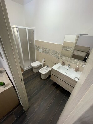 Une salle de bain moderne équipée d’une douche, de toilettes, d’un bidet et d’un espace lavabo.