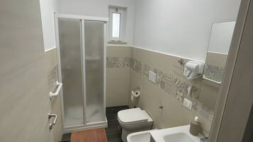 Et badeværelse med bruser, toilet, bidet og vask.
