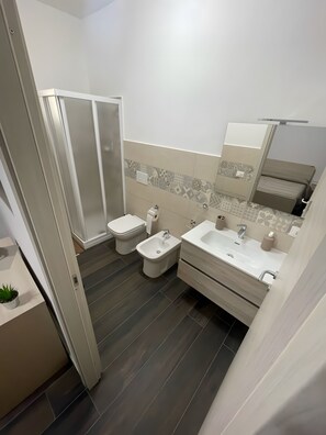 Une salle de bain moderne équipée d’une douche, de toilettes, d’un bidet et d’un lavabo.