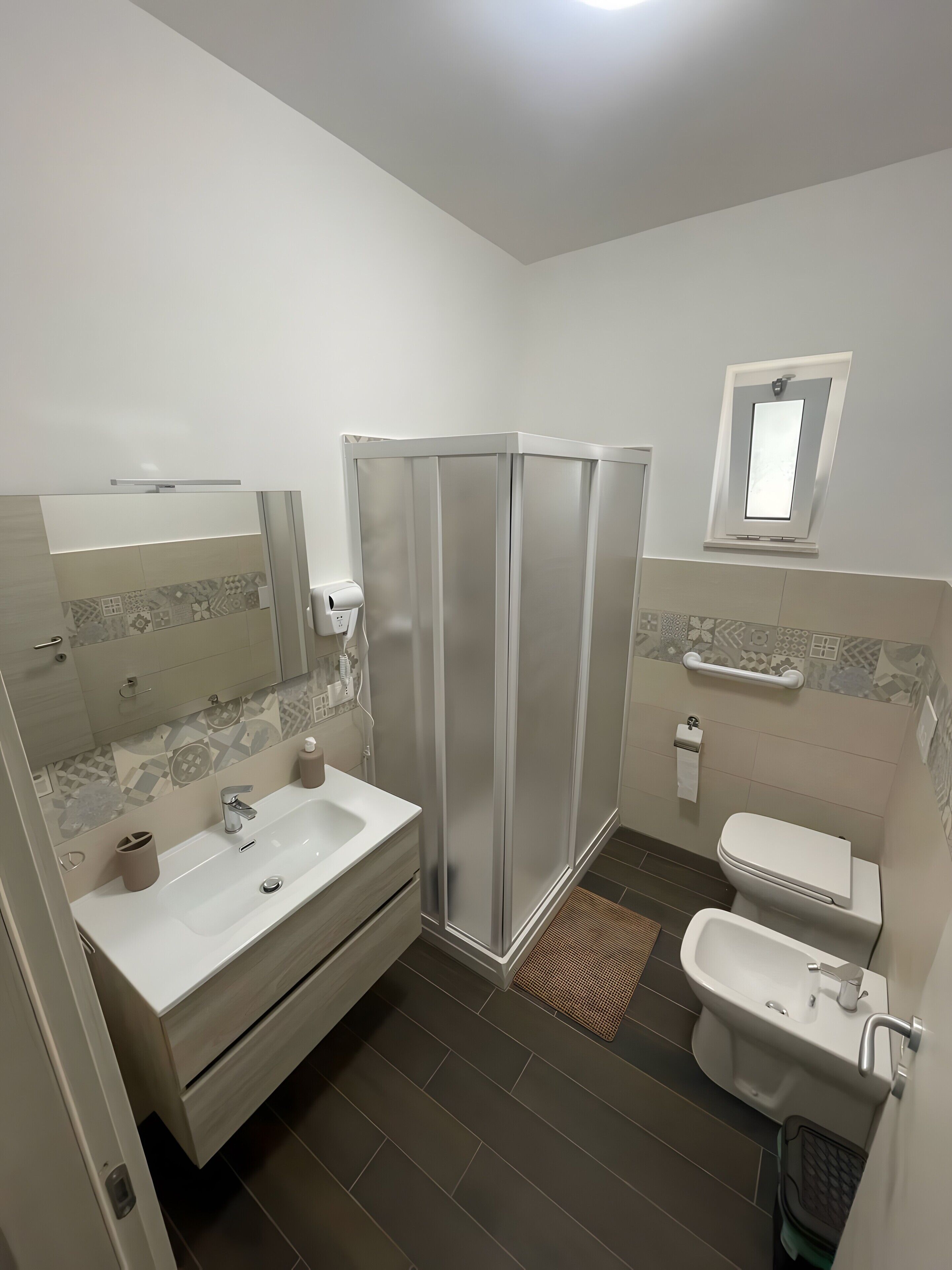A modern bathroom with a shower, sink, toilet, and a mirror.