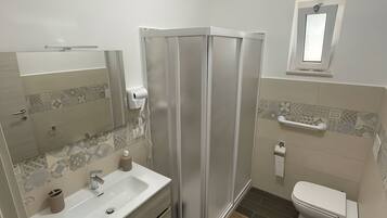 Une salle de bain moderne équipée d’une douche, d’un lavabo, de toilettes et d’un miroir.