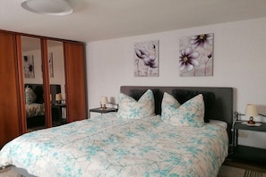 A bedroom with a bed, two nightstands, a wardrobe, and floral wall art. - Holiday home with 1 bedroom (Plau am See)