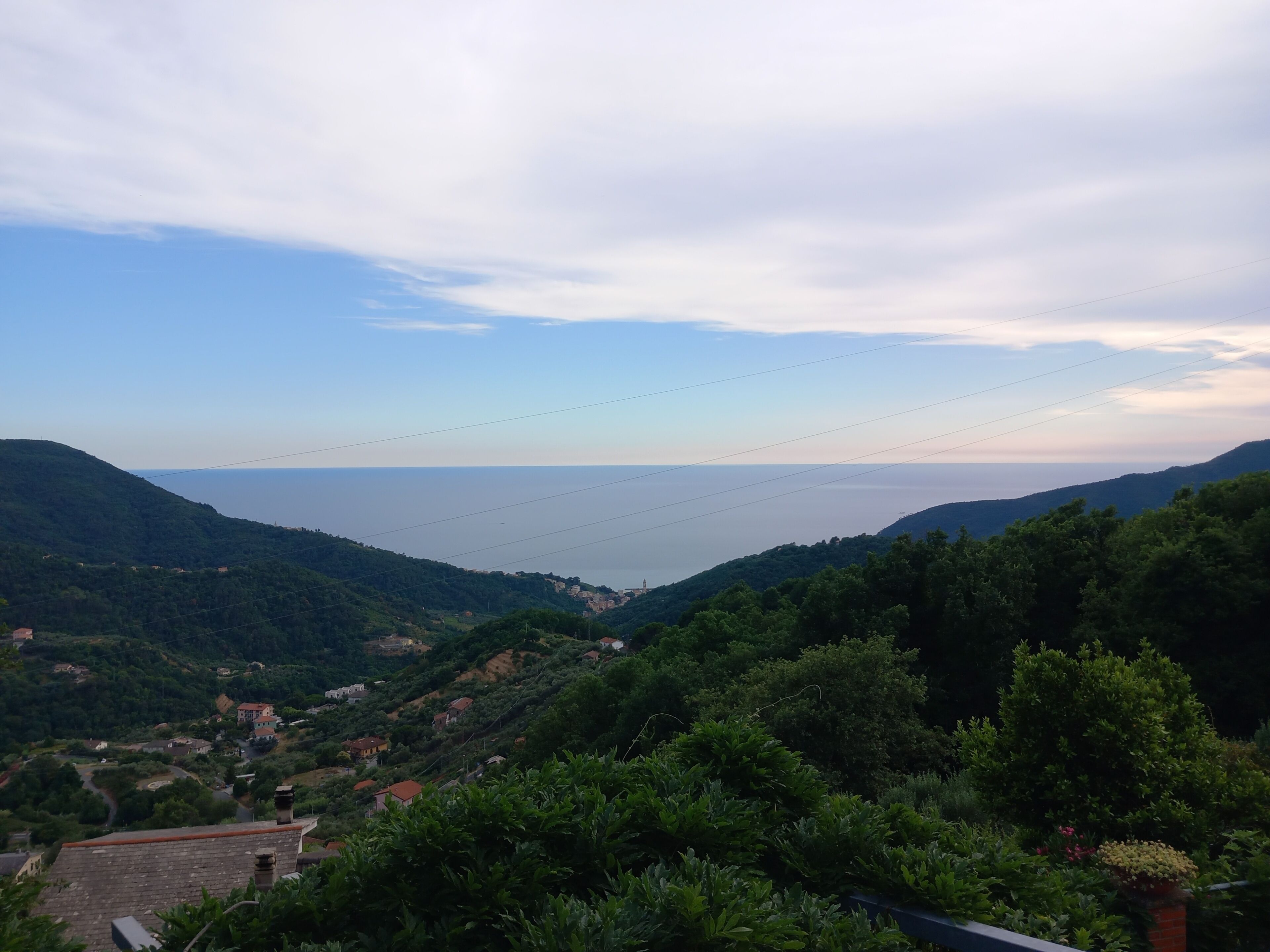 A coastal landscape with hills, a clear sky, and a distant view of the sea.