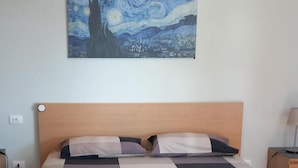 A bed with a checkered bedspread, a wooden headboard, and a painting above it. - B&B Bella Vita (Moneglia)