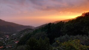 A hilly landscape with a sunset, power lines, and scattered buildings. - B&B Bella Vita (Moneglia)