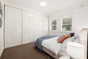 Ein Schlafzimmer mit Bett, Nachttisch und Kleiderschrank.