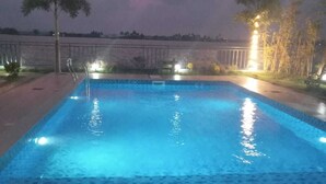 Piscina rectangular con borde de azulejos, rodeada por un muro bajo y una barandilla.