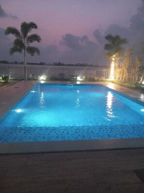 A rectangular swimming pool with a tiled edge, surrounded by a low wall and a railing.
