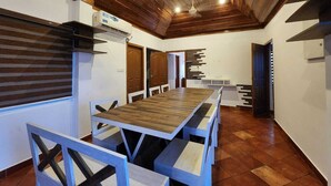 Una larga mesa de comedor con bancos, techo de madera y una zona de cocina moderna.