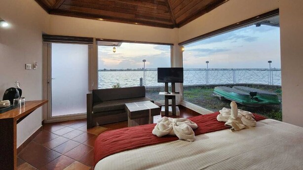 Un dormitorio con una cama grande, televisor, sofá y vista al agua.