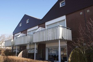 A residential building with a dark roof, white exterior walls, and a balcony with a white railing. - No. 2 in the Norderoog house (Borkum)
