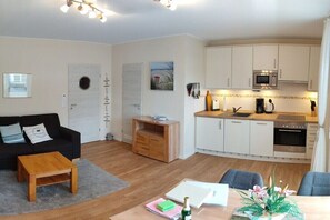 A compact living space with a kitchenette, a dining area, and a seating area. - No. 2 in the Norderoog house (Borkum)