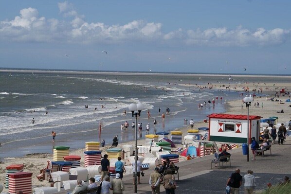 A beach with people, a lifeguard tower, and colorful beach huts. - No. 2 in the Norderoog house (Borkum)