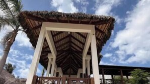 Un pabellón cubierto con un letrero que dice 'Cana Bay Beach Club' y un camino de piedra que conduce a él.