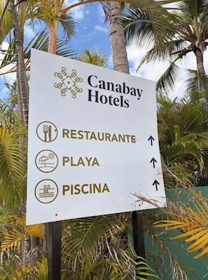 Schild für Canabay Hotels mit Pfeilen, die zum Restaurant, Strand und Pool weisen.