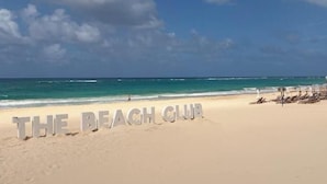 Una playa con las palabras 'THE BEACH CLUB' escritas en la arena.