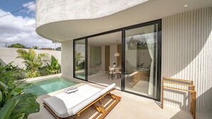 A modern poolside area with a lounge chair, a wooden drying rack, and a glass-enclosed dining area. - IVY Villa 2 (Pererenan)