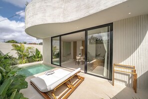 A modern poolside area with a lounge chair, a wooden drying rack, and a glass-enclosed dining area. - IVY Villa 2 (Pererenan)