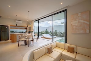 Un interior moderno con cocina, comedor y zona de estar con vistas al exterior.