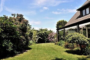 A house with a well-maintained lawn, a glass conservatory, and a variety of shrubs and flowers. - House with lake view (Ratzeburg)