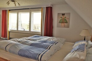 Une pièce avec un lit, une fenêtre, un radiateur et une lampe.