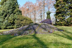 A garden with a large conical structure covered in flowers, surrounded by trees and grass. - Holiday apartment with 2 bedrooms (Eigeltingen)