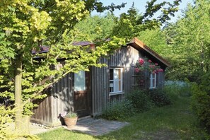 A wooden cabin with a porch, surrounded by greenery and a small garden. - Holiday home in Mölln with swimming pool (Mölln)