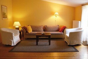 A room with a sofa, two chairs, a small table, a lamp, and a radiator. - Holiday home in Mölln with swimming pool (Mölln)