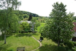 Üppige grüne Landschaft, ein Pfad führt zu einem Gebäude mit weißer Fassade.