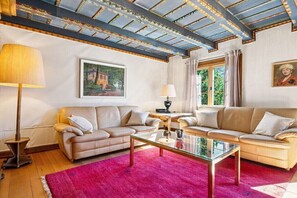 A living room with two sofas, a glass coffee table, a lamp, and a painting on the wall.