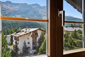 Une vue sur la montagne, visible depuis une fenĂȘtre dotĂ©e dâun cadre en bois et dâune poignĂ©e de porte.