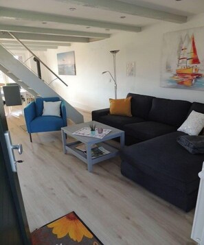 Ein modernes Wohnzimmer mit einer Couch, einem Sessel, einem Couchtisch und einer Treppe.